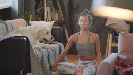 woman doing yoga at home with her dog