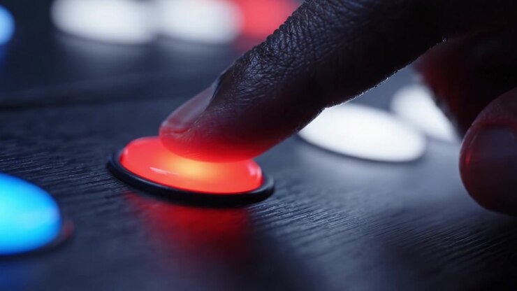 Close-Up de uma Mão Pressionando um Botão Colorido em um Painel de Controle, Demonstrando a Interação Entre Toque e Tecnologia Digital em um Ambiente Dinâmico