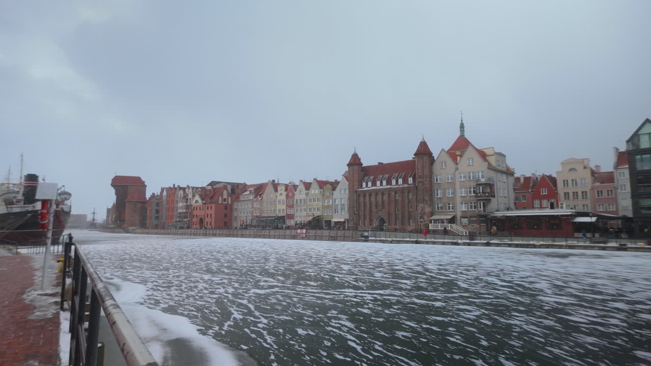 En naturskøn udsigt over den historiske arkitektur i Gdansk Gamle By langs den frosne Motlawa-flod i Polen på en kold vinterdag.