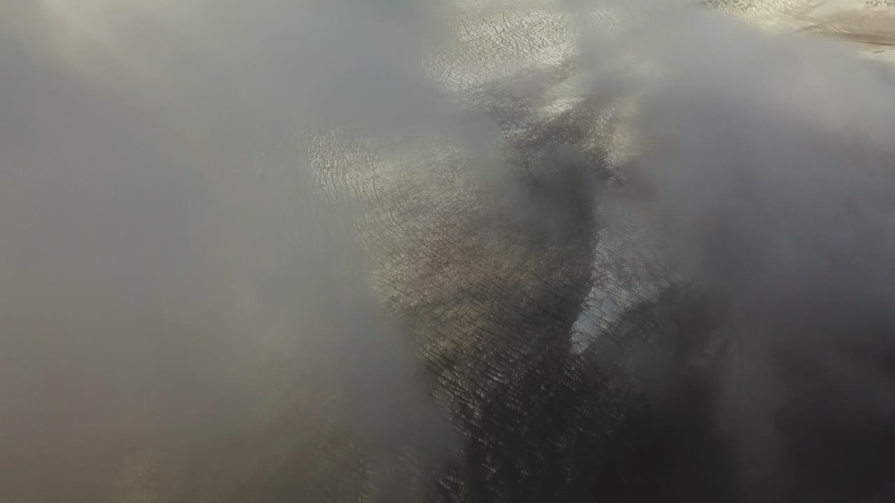 Aerial landscape view going through clouds, over the textured ice surface of an icelandic glacier
