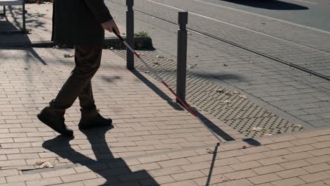 lone blind man detecting tactile tiles, walking to pedestrian crossing safe road