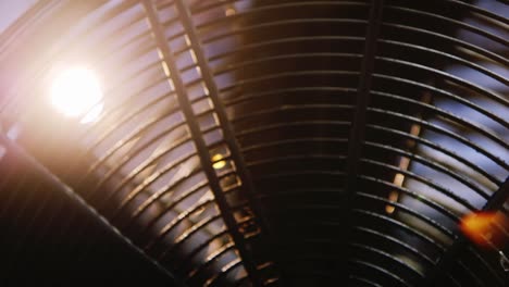 rays of light shine through the blades of a rotating industrial fan 1