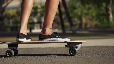 Cámara-Lenta-Enmarca-El-Viaje-De-Una-Joven-En-Longboard-Cerca-De-Palmeras,-Su-Vestimenta-Veraniega-De-Pantalones-Cortos-Y-Zapatillas-De-Deporte-Añade-Atractivo