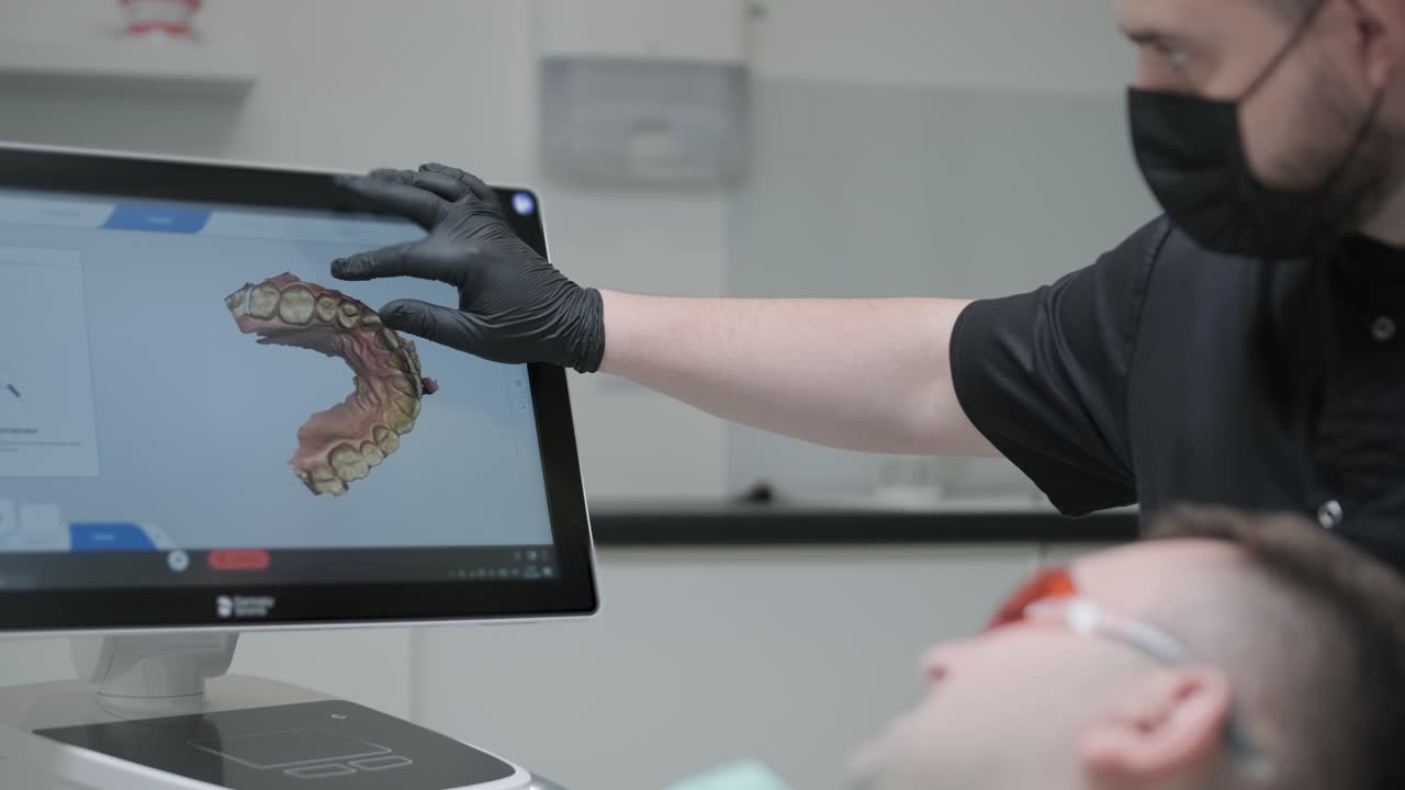 el médico escanea los dientes del paciente en la clínica. el dentista sostiene en su mano un escáner 3d manual para la mandíbula y la boca. salud dental. crea un modelo 3d de dientes y encías en un monitor médico.