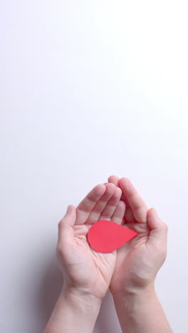 vertical video of hands of caucasian man holding blood drop on white background with copy space