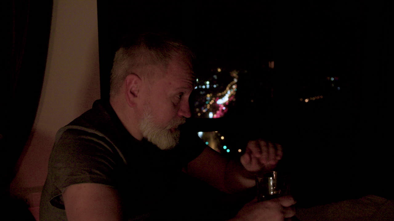 anciano bebiendo cerca de la ventana