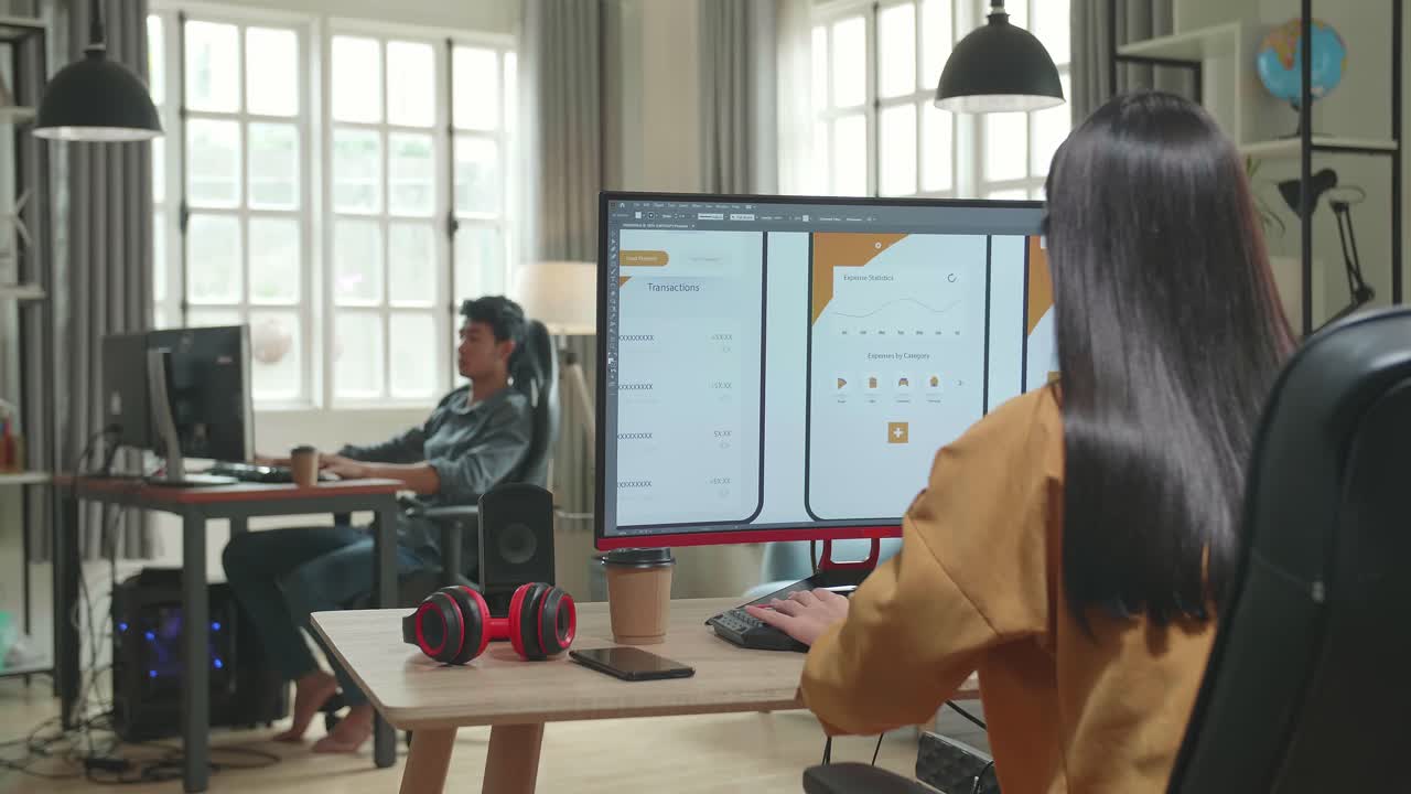 Back View Of Asian Female Mobile Application Developer Works With Graphics On Her Personal Computer In Office