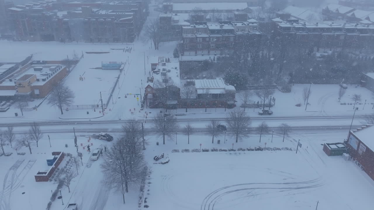 Aerial footage following a small car driving through the snow on Market Street during a snowstorm in Chattanooga, TN.