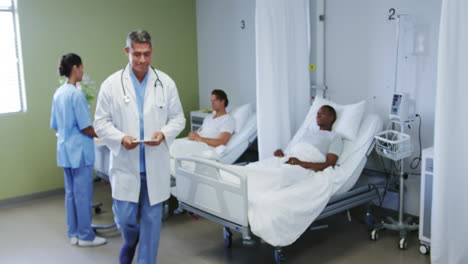 front view of caucasian male doctor talking with patient in ward at hospital