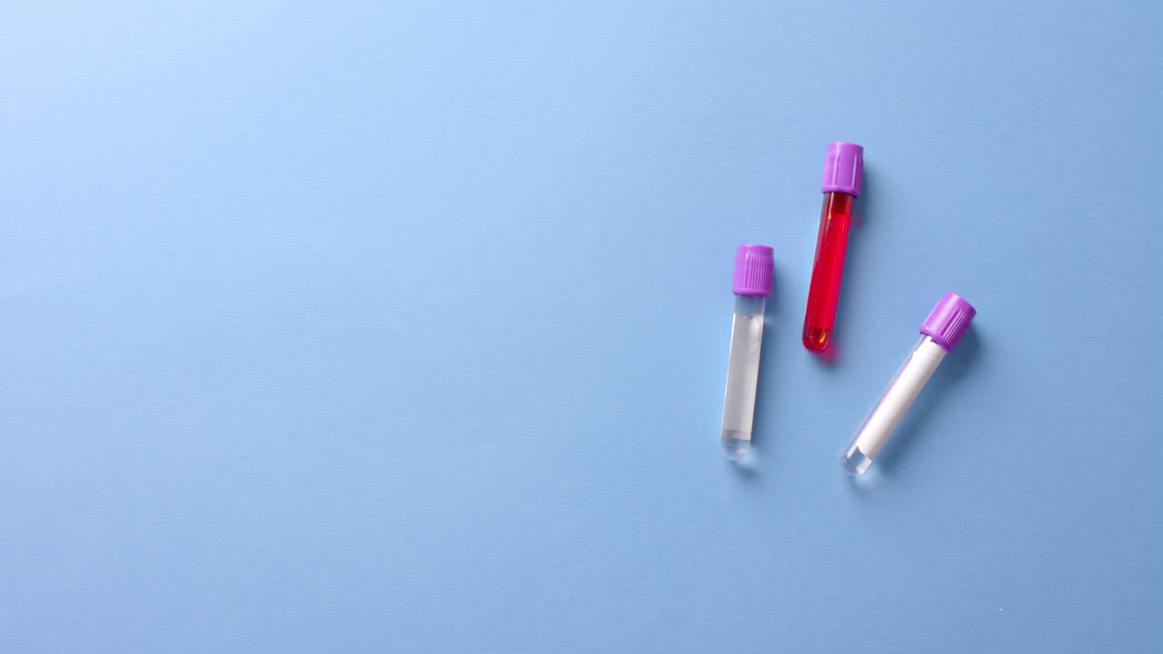 Close up of blood samples on blue background with copy space, slow motion