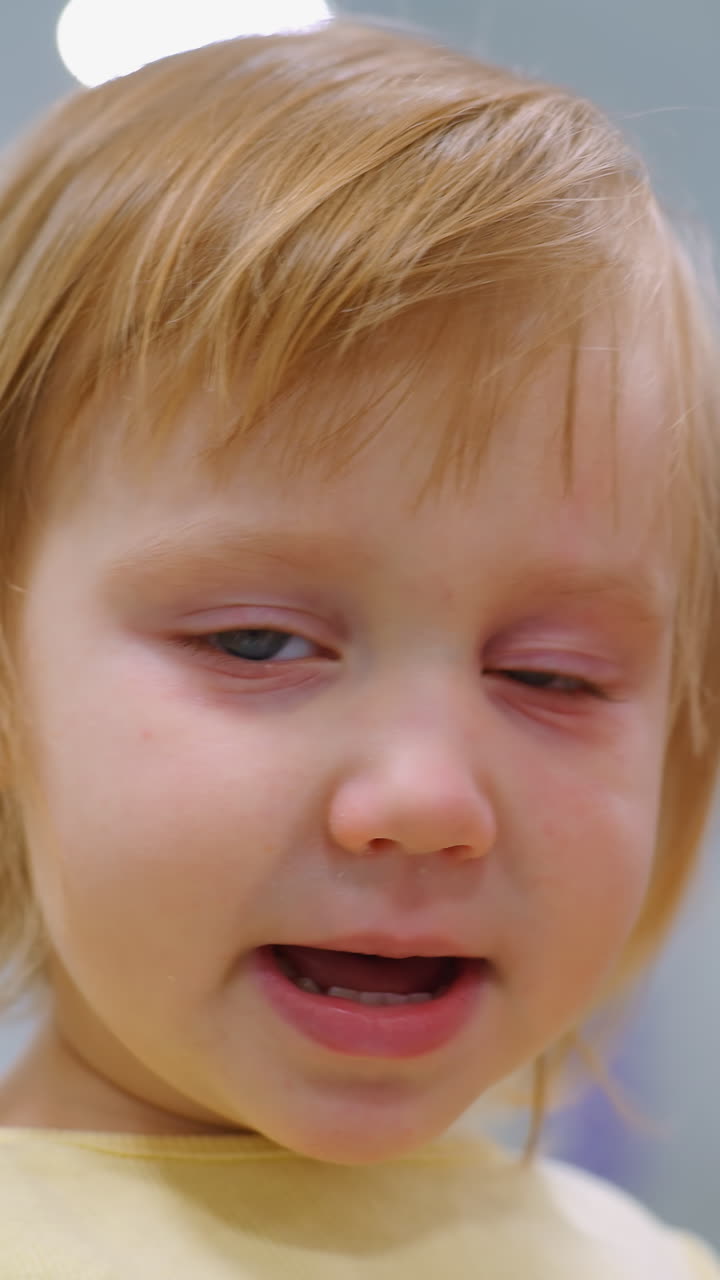 primer plano de un adorable niño pequeño de ojos azules que lleva un traje amarillo, llevado por la madre mientras mira contemplativamente, una expresión cálida con una iluminación suave aumenta la profundidad emocional