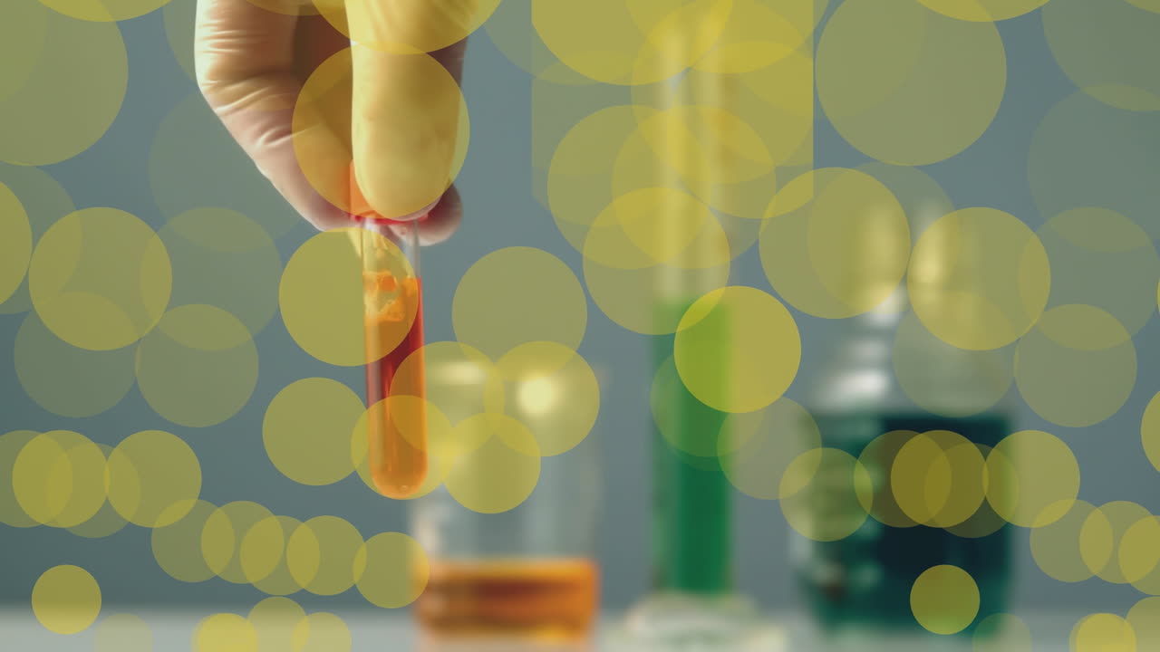 실험실 직원의 손 위에 노란색 점의 애니메이션이  ⁇ 플을 흔들고 있습니다.