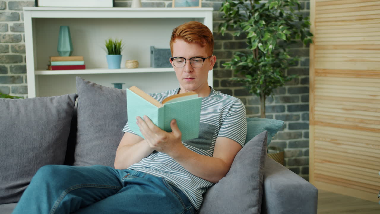 un joven leyendo un libro en un sofá