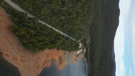 Vertical-drone-shot-of-Lake-Huntsman-with-green-dense-mountains-in-Tasmania