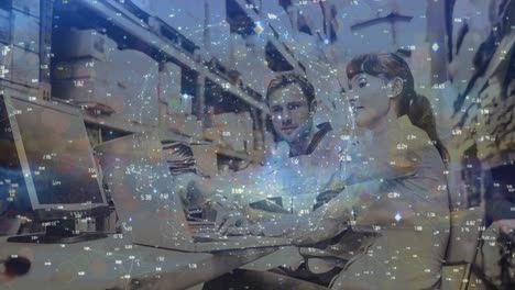 globe of network of connections spinning over male and female supervisor using laptop at warehouse