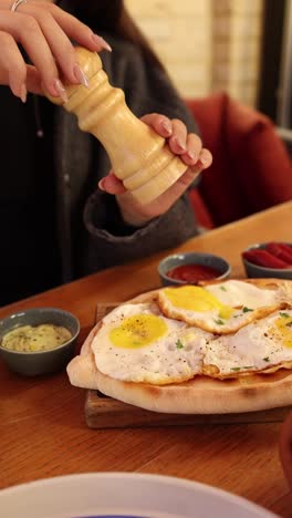 woman seasoning eggs on a flatbread