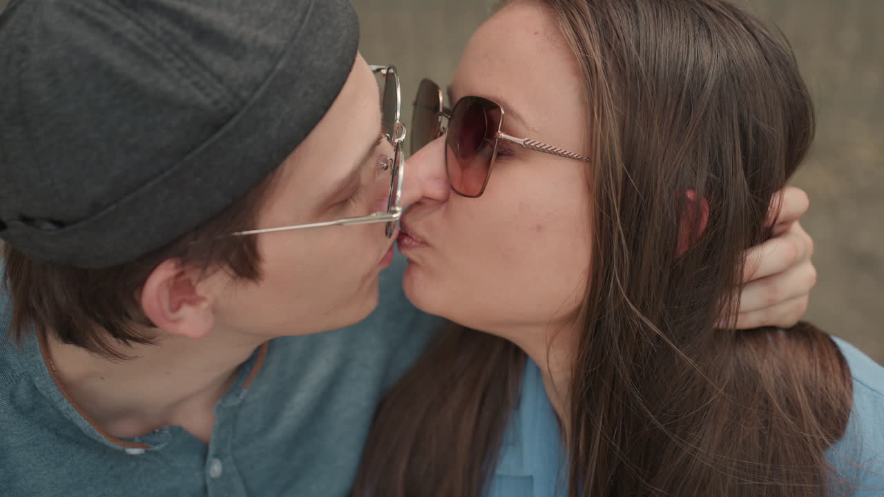 Pareja compartiendo un momento íntimo, una pareja disfruta de un tierno beso, dos enamorados se acercan para un beso suave, una pareja sentada en un banco intercambia miradas cariñosas con un entorno apacible cerca