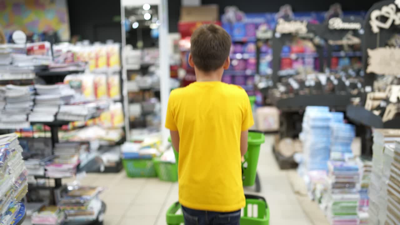 Stationery shop in the mall. Boy with shopping cart with different stationery for school