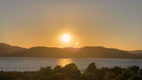 beautiful and romantic seaside sunset cinemagraph with some wind moving gently at the atlantic coast of portugal, and the sun disappearing behind a mountain