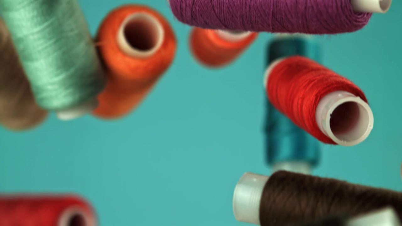 Assorted Colorful Sewing Thread Spools on Teal Background