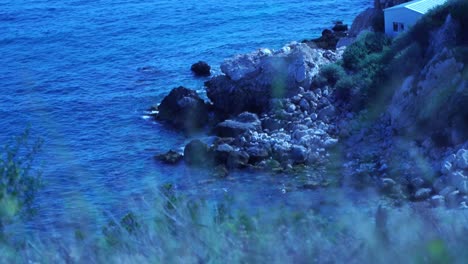 rocks on the sea in a bay in southern france filmed through grass