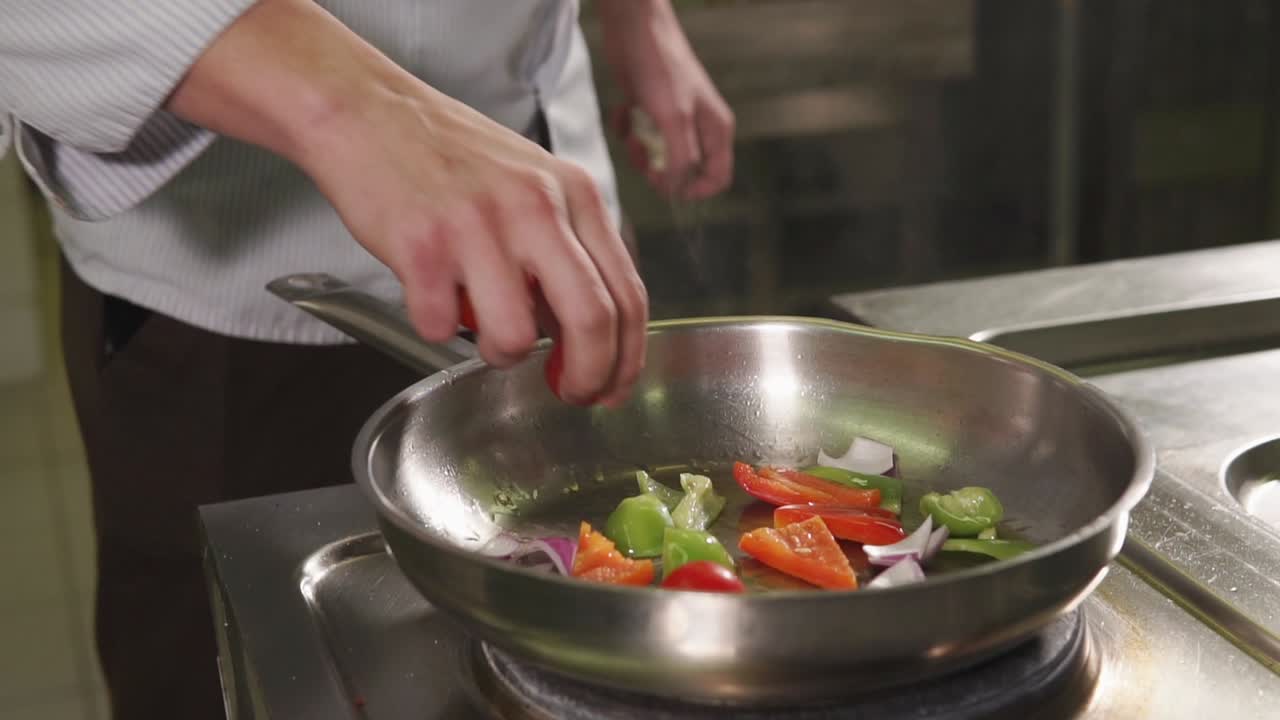 요리사 가 팬 에 채소 를 준비 하고 있다
