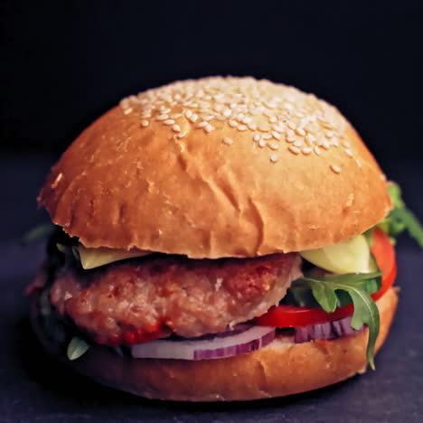 great burger with beef cutlets, tomatoes, lettuce with melted cheese rotates on a wooden board on black background.