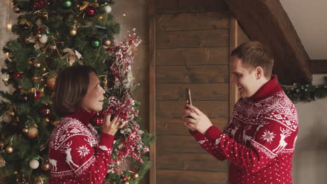 man taking a funny video of his wife while she holding a christmas wreath at home