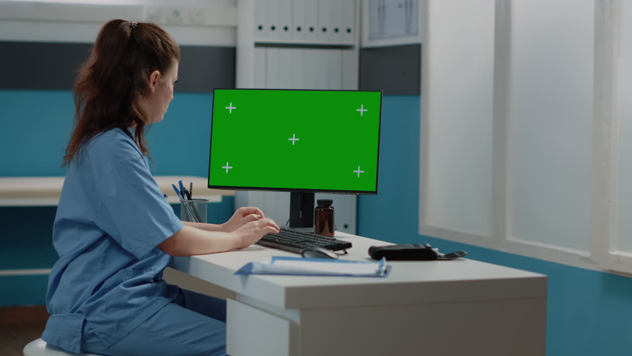 Nurse working on computer with green screen
