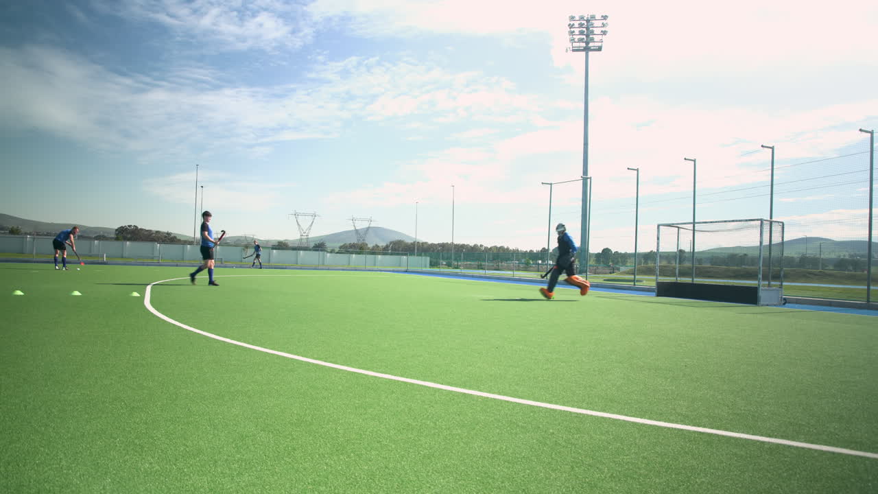 Playing field hockey, male players practicing on outdoor turf field