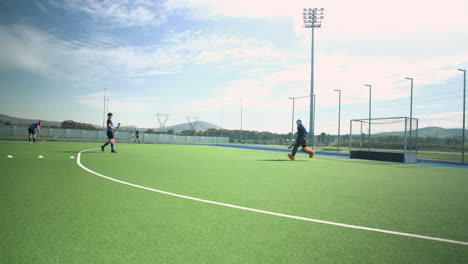 playing field hockey, male players practicing on outdoor turf field