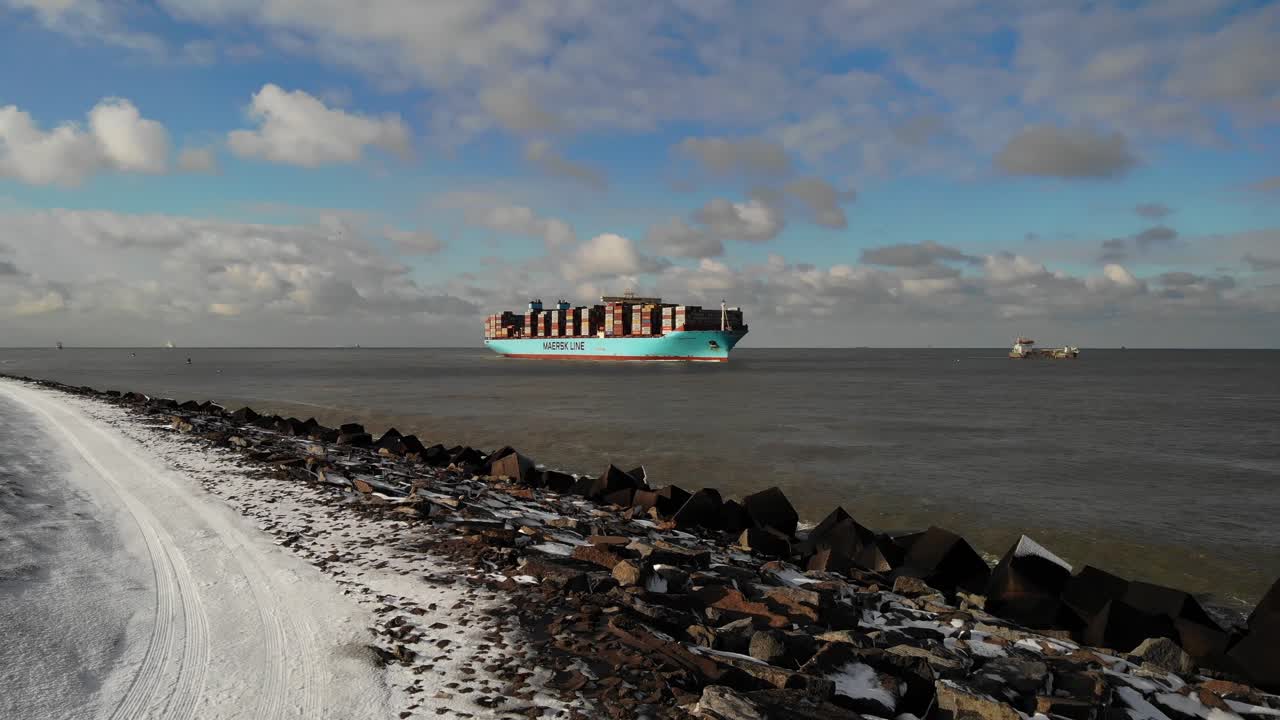Giant container vessel named Marstal Maersk navigating into the port of Rotterdam on a cold sunny winter day. Drone pedestal shot