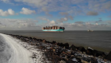 giant container vessel named marstal maersk navigating into the port of rotterdam on a cold sunny winter day. drone pedestal shot