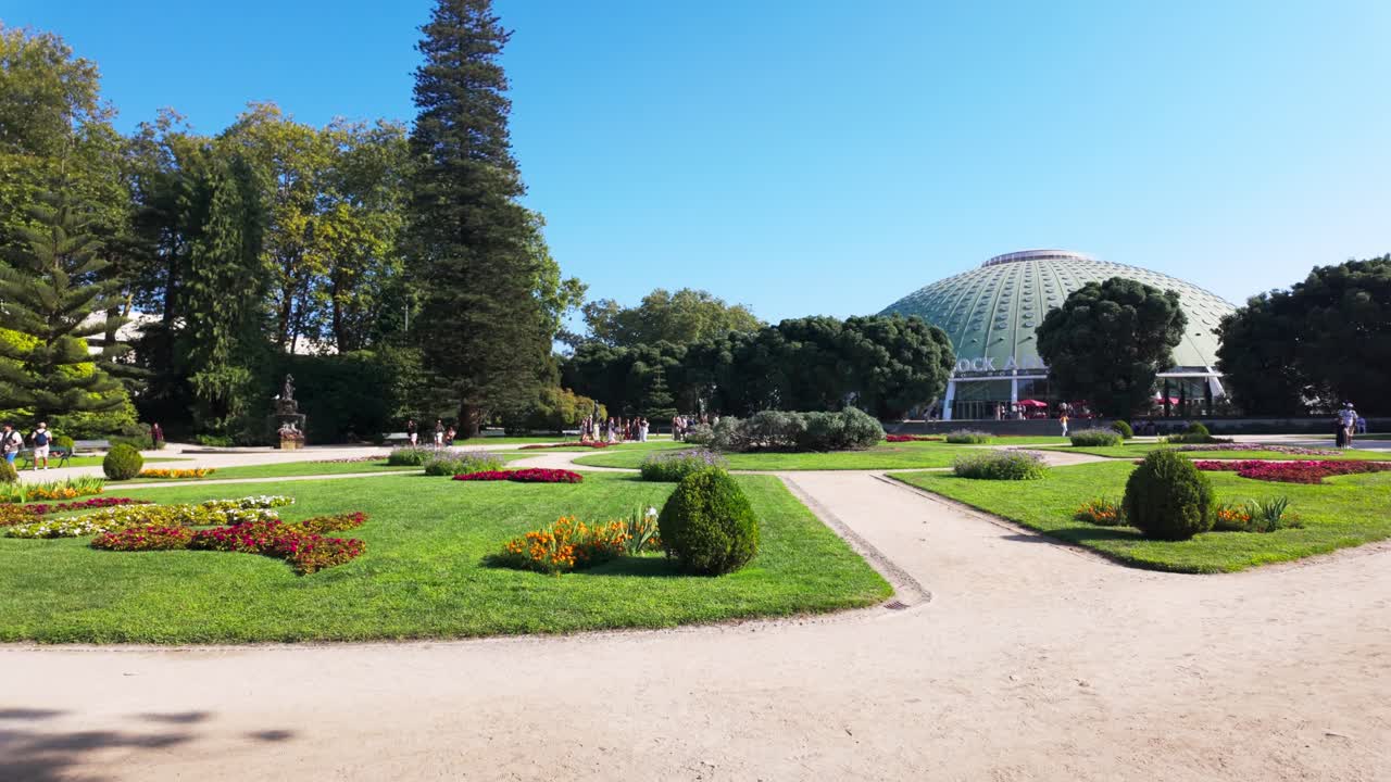 Sunny day in Porto's Jardins do Palácio de Cristal with people strolling on a peaceful pathway
