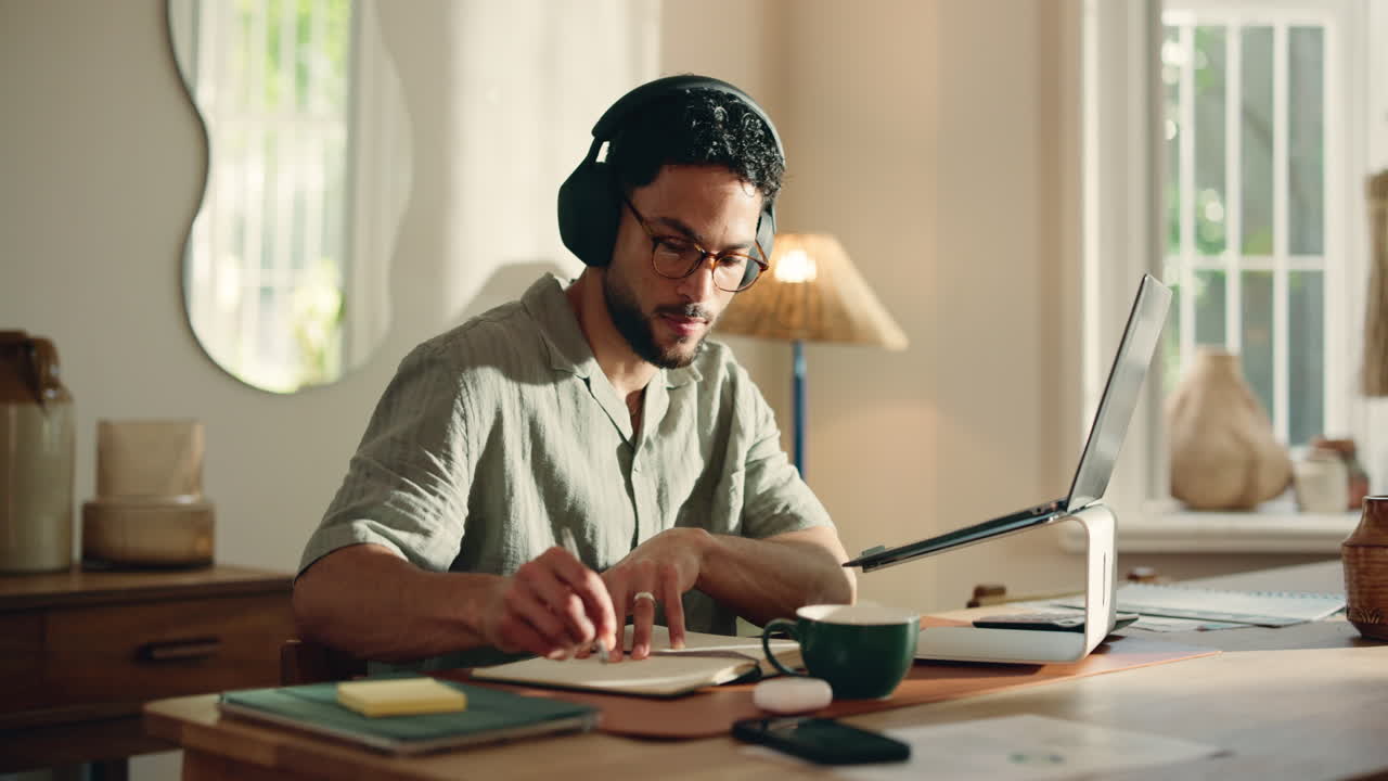 Young Man in Headphones Working and Writing at Home Office Desk