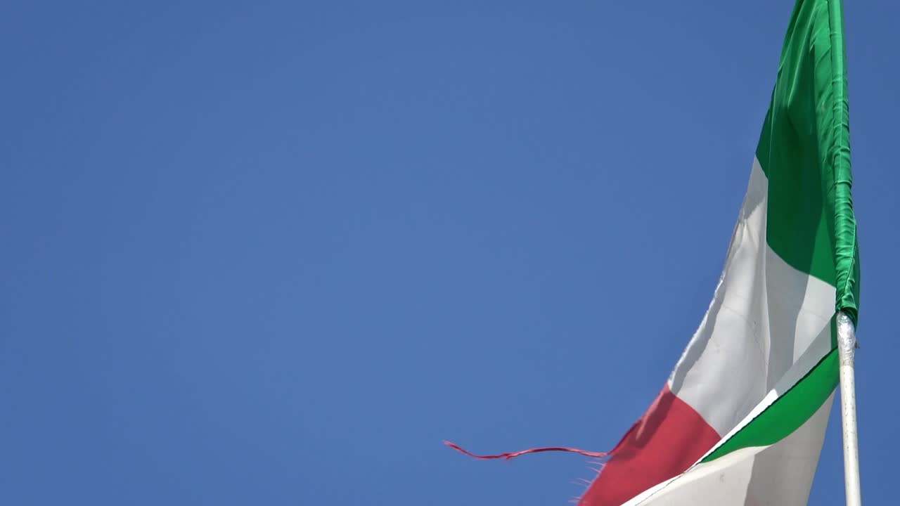 4K. Bandiera nazionale italiana che sventola al vento su un cielo blu. Bandiera italiana