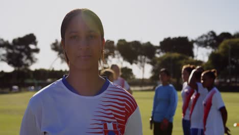 Female-soccer-player-standing-while-teammates-talk-on-soccer-field.-4k