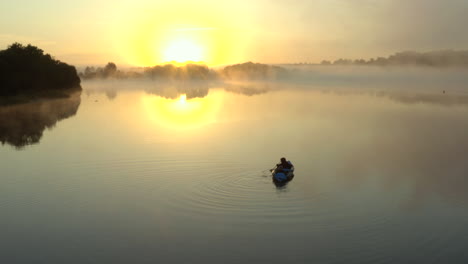 drone footage of misty sunrise morning of people kayaking on a lake in the english countryside