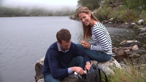 couple on a walk taking a break by the edge of a lake