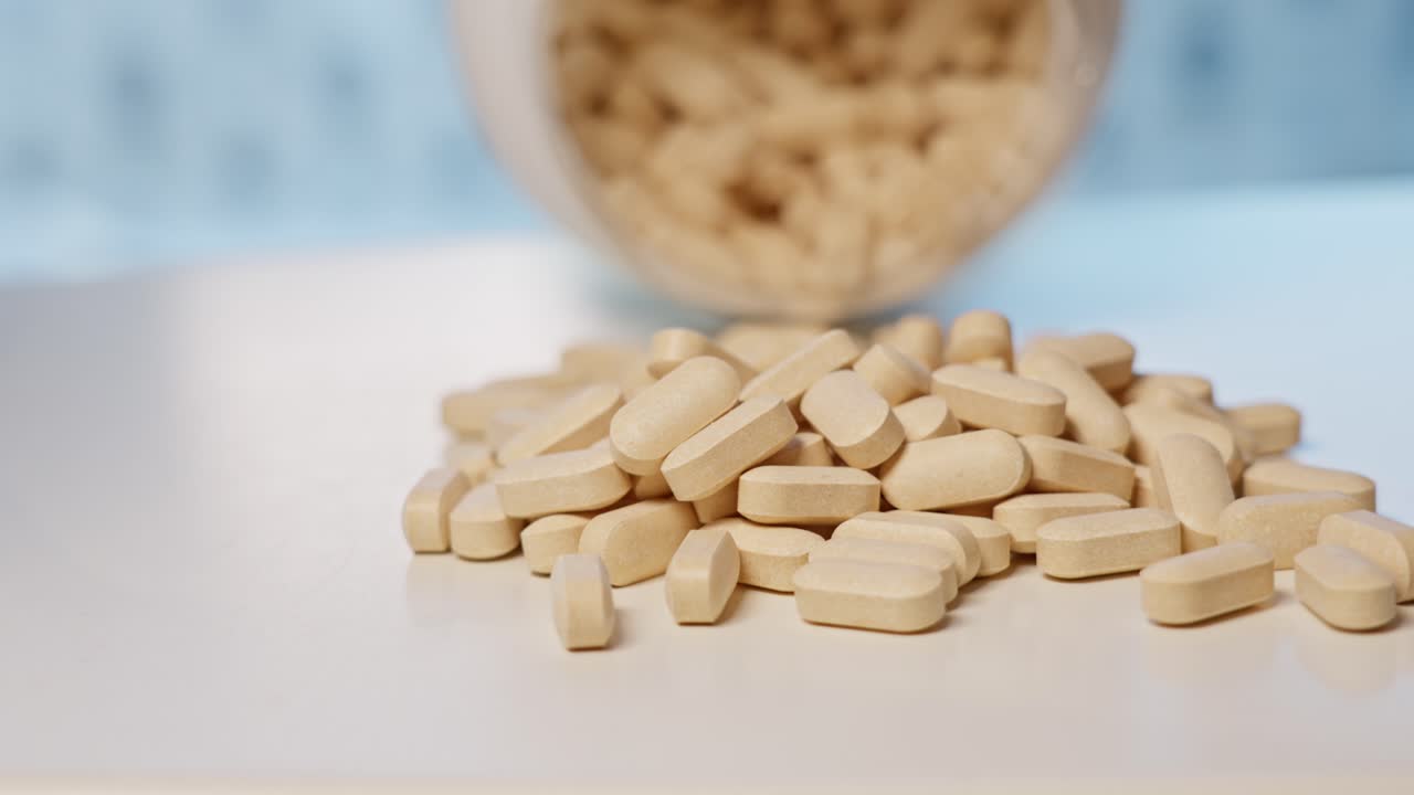 tabletas de vitamina c vertidas de la botella en la mesa, movimiento lento de cerca