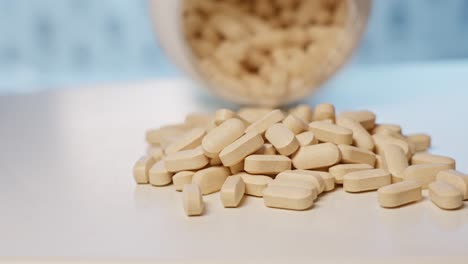 Vitamin-C-tablets-poured-out-of-bottle-onto-table,-close-up-slow-motion