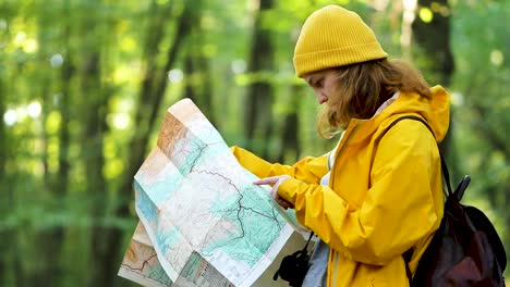 mujer orientándose con un mapa de papel en el bosque