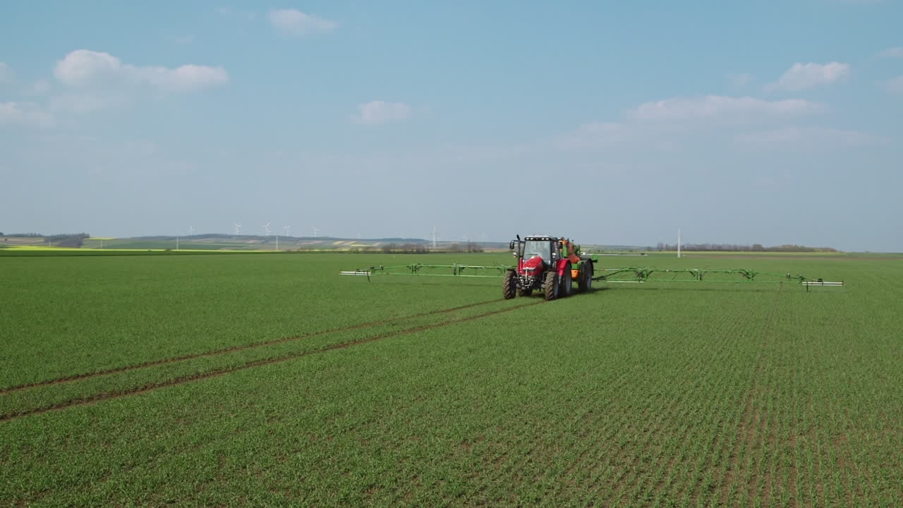 Trattore agricolo che applica pesticidi con irroratrice.