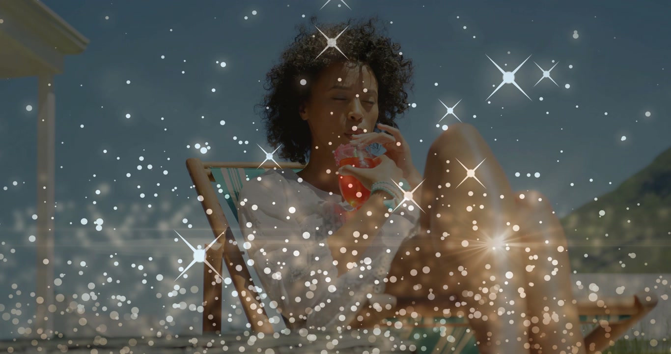 Adult woman lifting cup, sipping, cooling in beach chair, sparkles moving across her for marketing