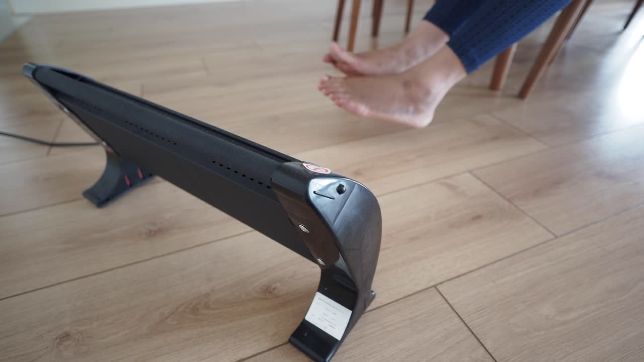 Person warming feet with floor heater
