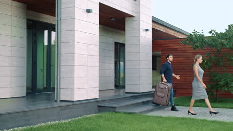 business people with luggage leaving luxury house