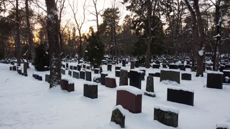 montón de tumbas cubiertas de nieve en un cementerio durante la puesta de sol