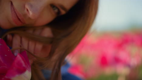 Closeup-pink-tulip-flower-and-unknown-woman-face-on-floral-background-outdoors.