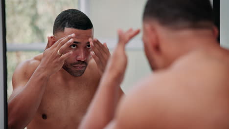 man applying skincare product in mirror
