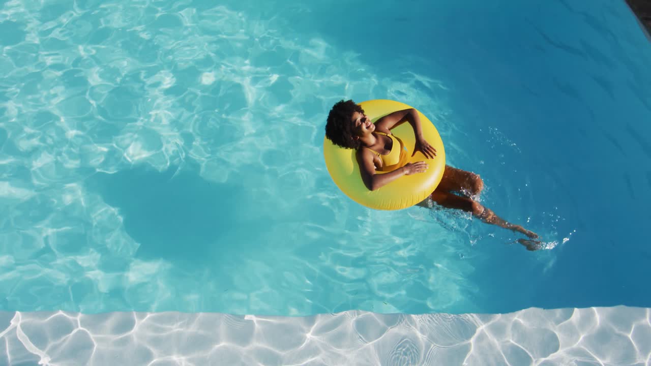mujer de raza mixta divirtiéndose tomando el sol en inflable en la piscina